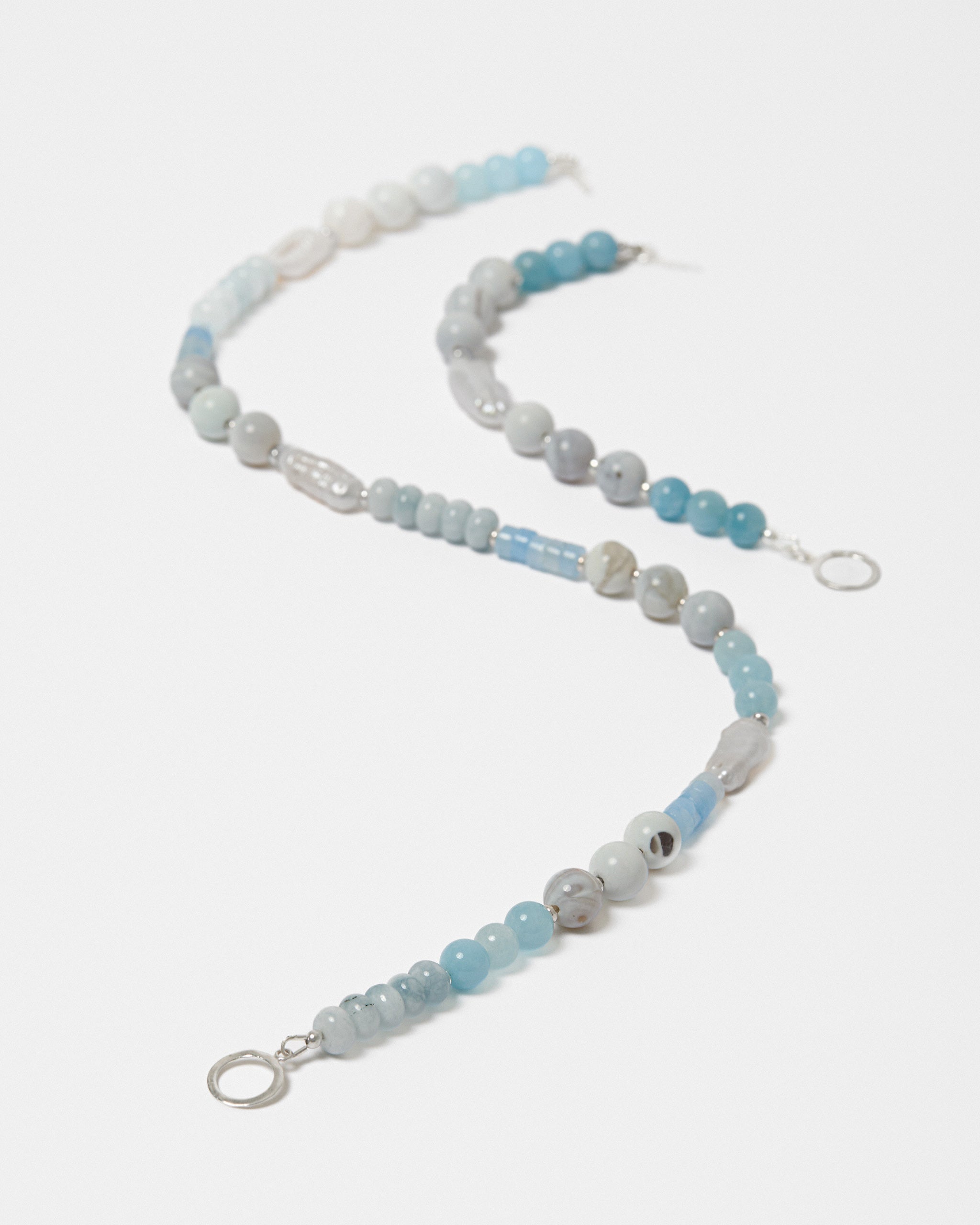 Beaded jewellery with blue and freshwater pearl beads on a white background