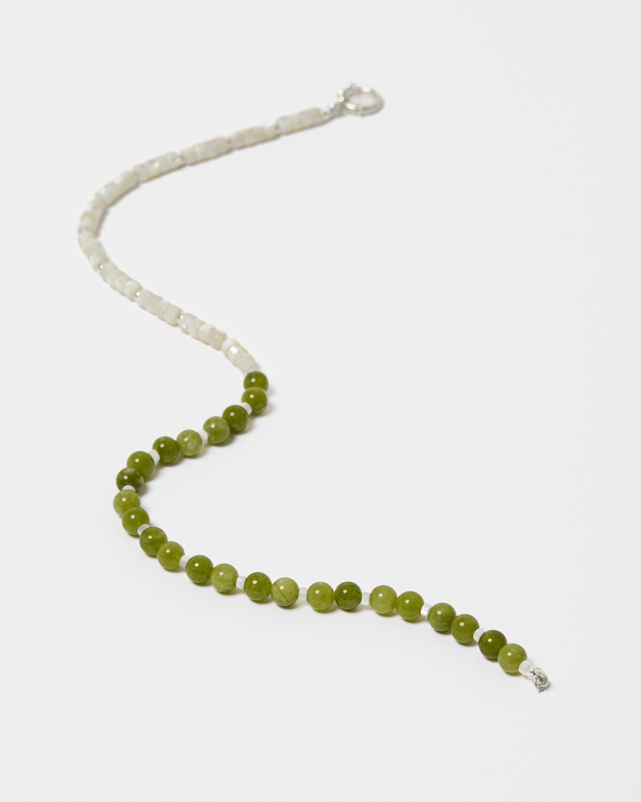 Necklace with green beads and a silver clasp on a light grey background