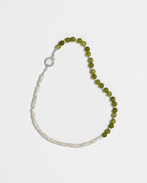 A beaded necklace, made out of white and green beads, on a white background