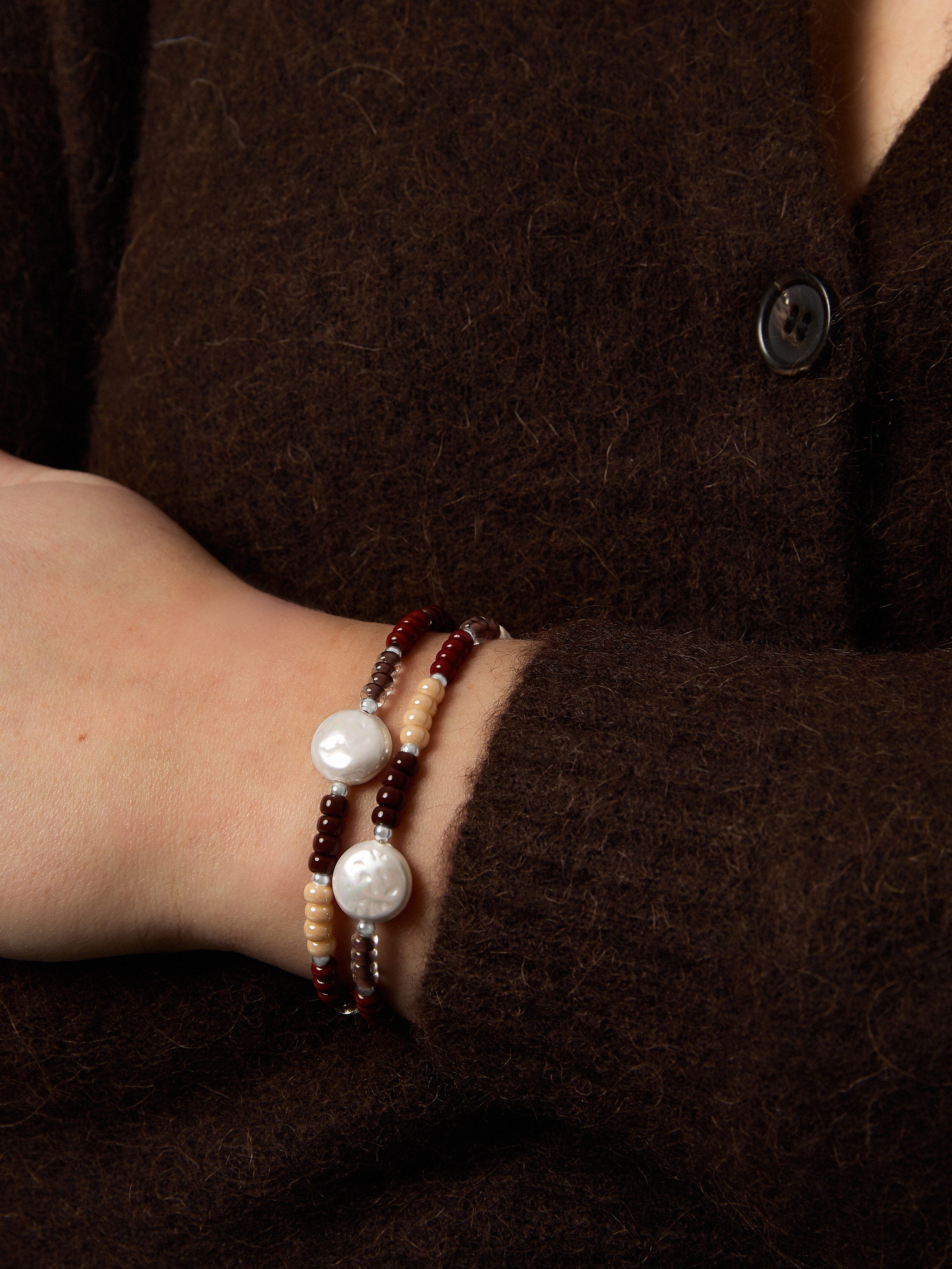 Close-up of a wrist wearing two pearl bracelets