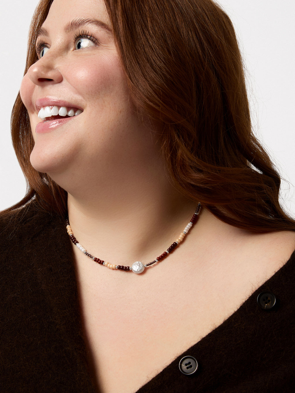 Woman wearing a beaded necklace on a plain background