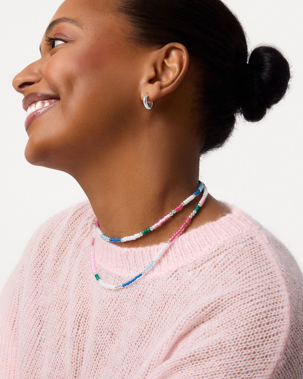 Woman wearing colourful beaded necklaces against a light background